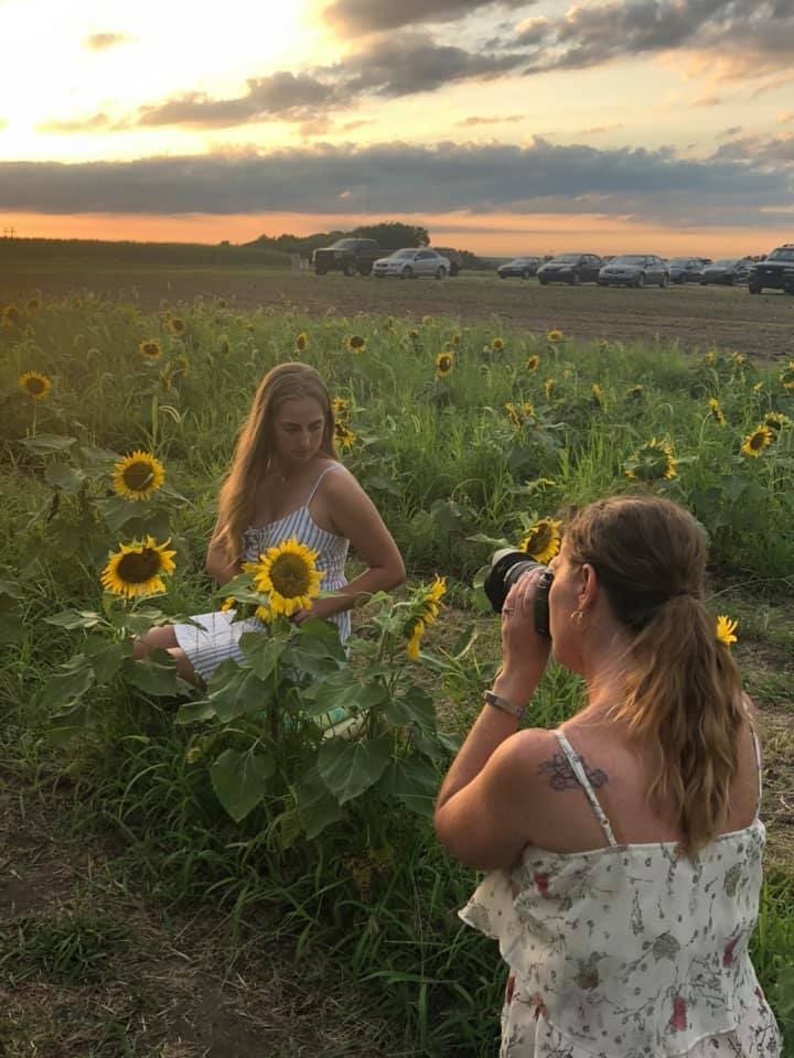 Kansas City senior photographer photographing a high school senior in a sunflower field during golden hour for a summer senior portrait session.